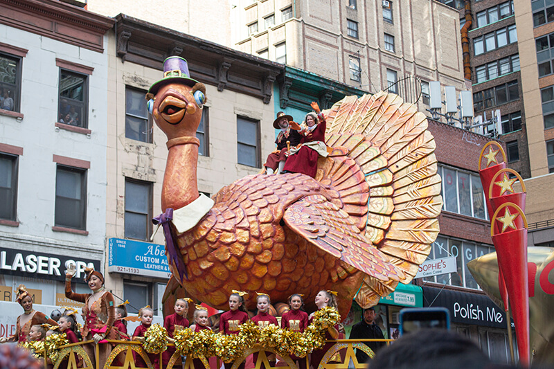 Two people sit on top a giant turkey, one of the floats at the Macy's Thanksgiving Day Parade floats